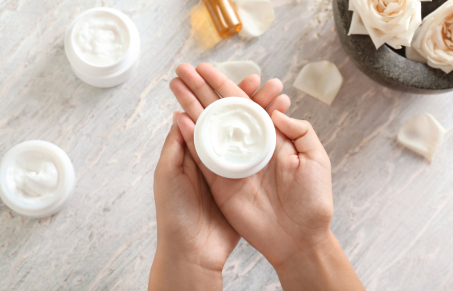 Hands holding jar of moisturizing cream.