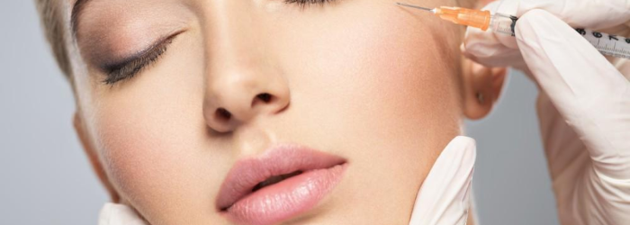 Woman receiving cosmetic injection near eye.