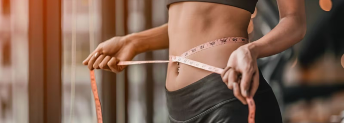 Woman measuring waist with measuring tape.