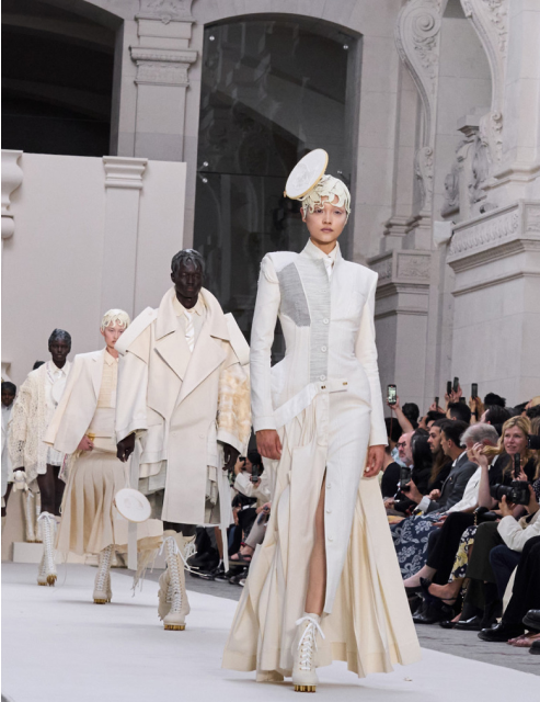 Fashion show with models in white outfits.