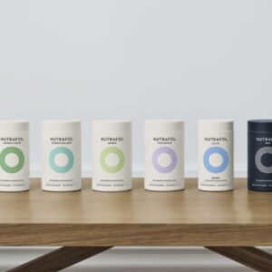 Six Nutrafol bottles on a wooden table.