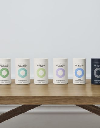 Six Nutrafol bottles on a wooden table.