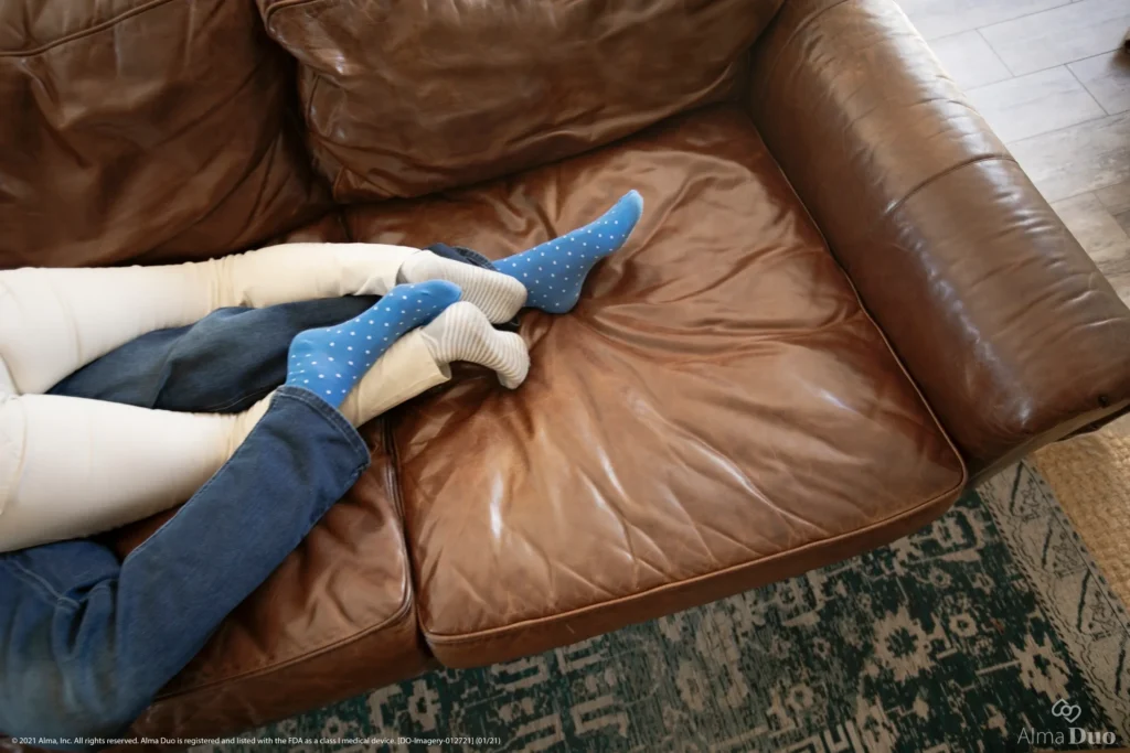 Two people lounging on a leather sofa.