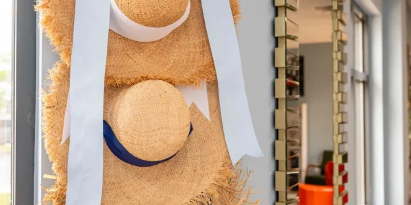 Four straw hats with colorful ribbons hanging.
